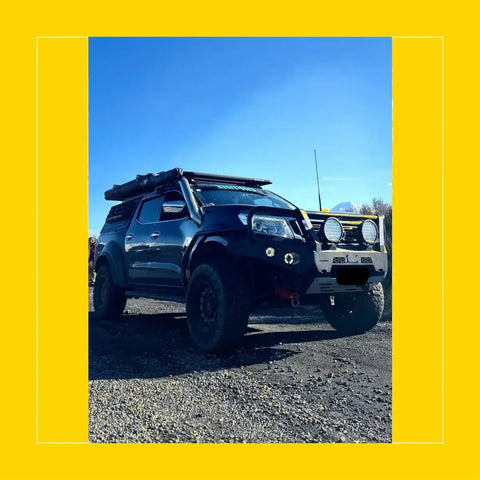 Black nissan navara np300 d23 with rugged roof rack and dual round headlights featuring rockarmor steel rockslider side steps