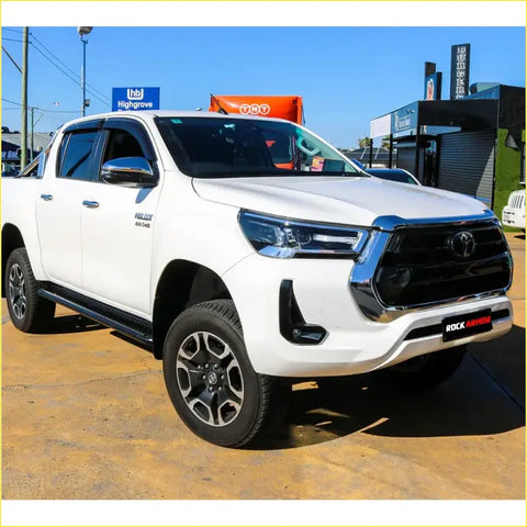 White toyota hilux 4wd ute with black grille featuring rockarmor steel rockslider side steps for offroad use