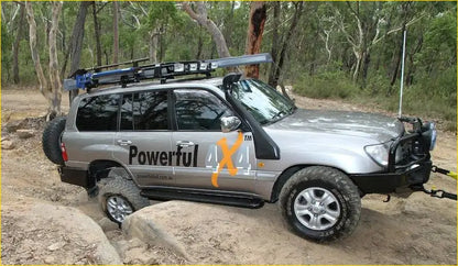 Silver toyota land cruiser 70 series with black roof rack and off-road tires featuring rockarmor steel rockslider side steps