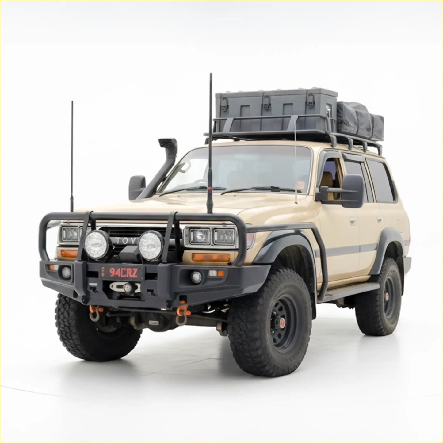 Beige toyota land cruiser with black rockarmr premium steel bullbar roof rack carrying gray storage box and bag