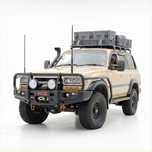 Beige toyota land cruiser with black rockarmr premium steel bullbar roof rack carrying gray storage box and bag