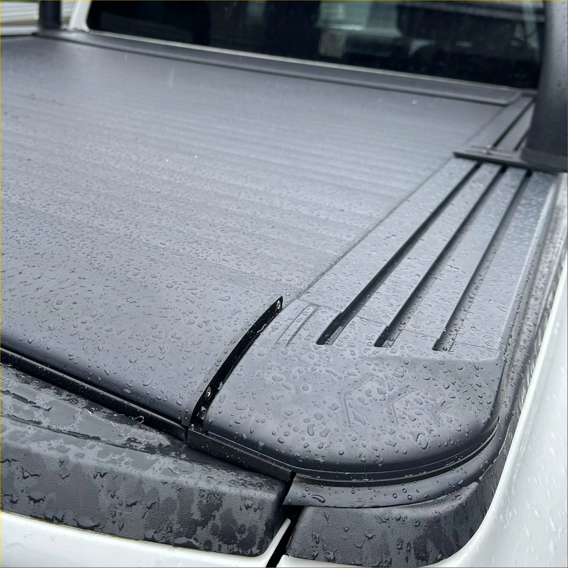 Black textured hard tonneau cover with integrated side rails for ford ranger 2022 plus shown from the back side