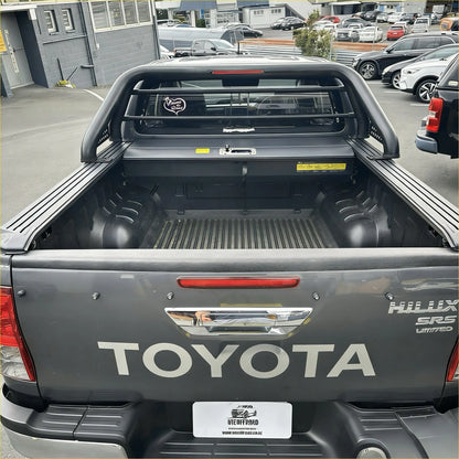 Back of black toyota hilux srs limited pickup with rugged bed liner and chrome tailgate handle featuring roll bar t10 and manual roller shutter