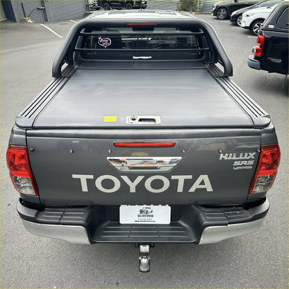 Back view of dark gray toyota hilux srs limited with black manual roller shutter roll bar t10 bed cover 2015-2025