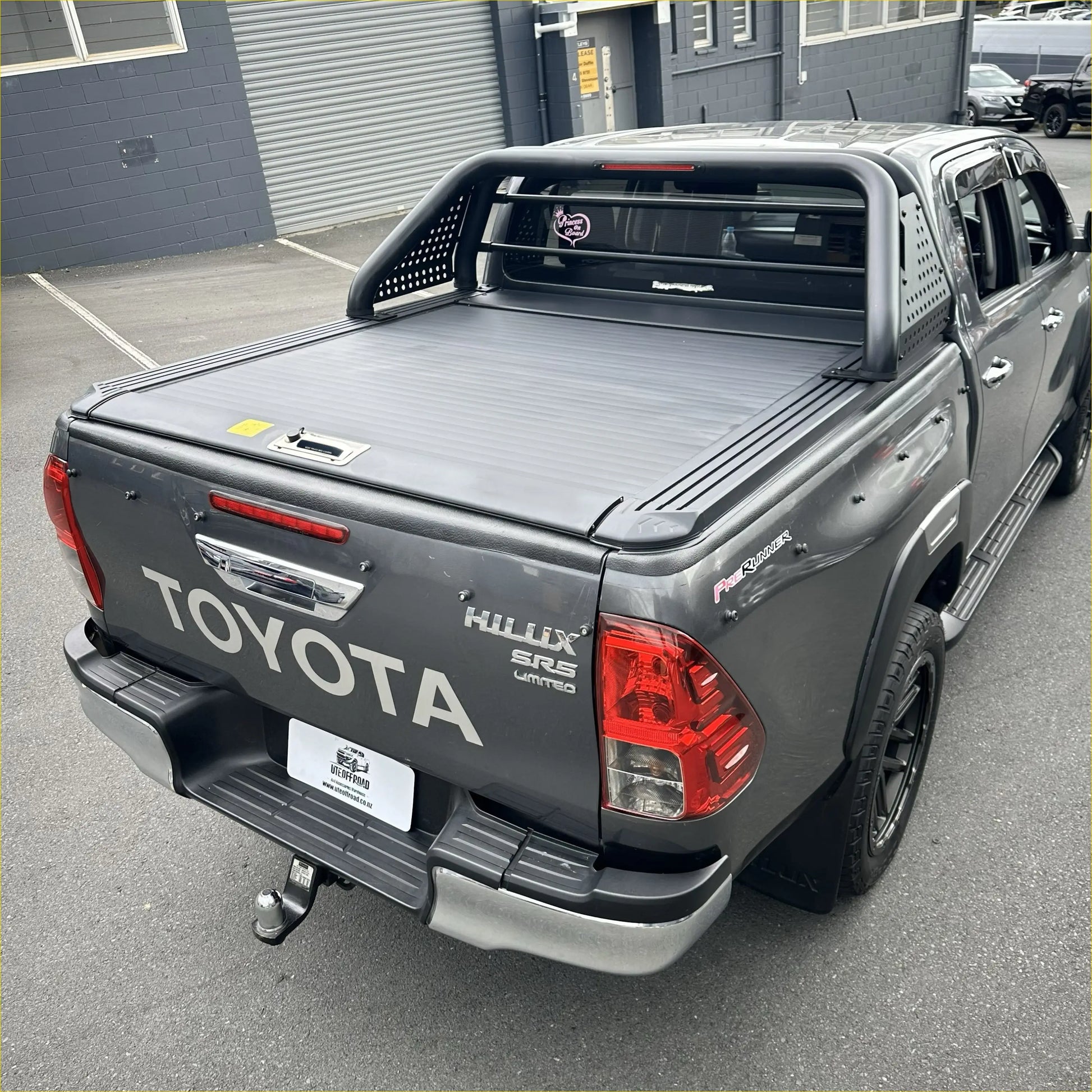 Gray toyota hilux sr5 limited with black manual roller shutter and roll bar t10 shown from the back side