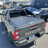 Dark gray toyota hilux pickup with black manual roller shutter and chrome roll bar t20 shown from the back side