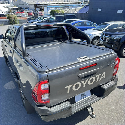 Dark gray toyota hilux pickup with black manual roller shutter and chrome roll bar t20 shown from the back side