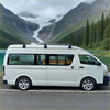 White toyota hiace van with black heavy duty 3 piece roof rack set and alloy wheels parked beside a lake
