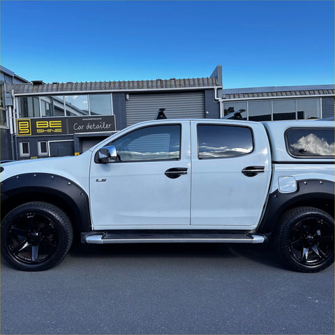 White mitsubishi triton pickup with black fender flares and hardtop canopy showing side step running board oem style