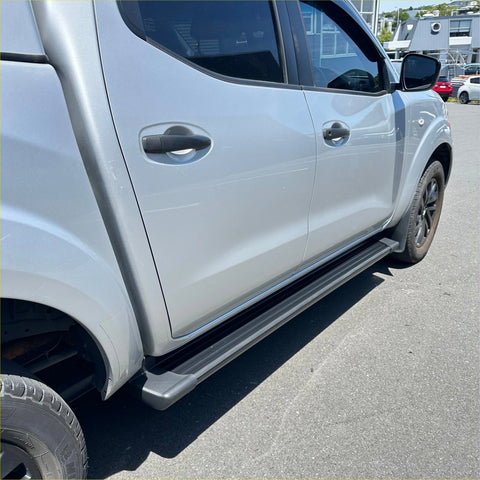 Black rubber side step running board along the lower edge of a silver nissan navara 2015-current double door