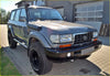 Dark gray metallic toyota land cruiser 100 with black off-road tires and roof-mounted snorkel for land cruiser 80 series