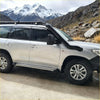 Silver toyota land cruiser 200 series 2017-2022 with black stainless steel snorkel and roof rack shown from the back side