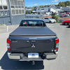 Dark gray mitsubishi triton double cab with black soft tonneau cover shown from the back side