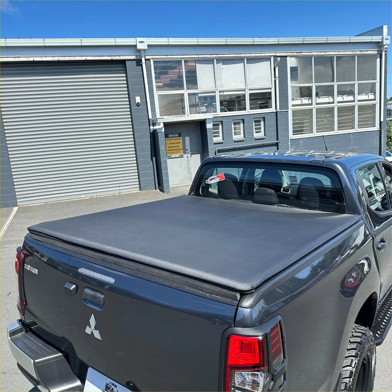 Black fabric soft tonneau cover on the back side of a mitsubishi triton 2015-2023 double cab pickup truck