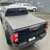 Black hard-shell tonneau cover on blue toyota hilux 2015-2020 sr5 double cab back side view