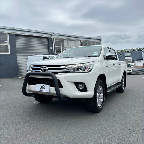 White toyota hilux pickup truck featuring a matte black stainless steel nudge bar and black front bumper guard