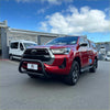 Red toyota hilux pickup with stainless steel nudge bar 2021-2025 featuring black bumper guard and chrome accents