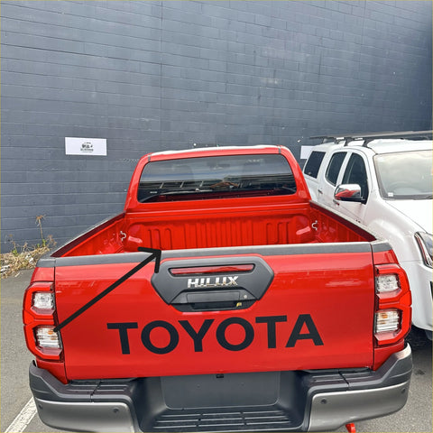 Back view of red toyota hilux 2021 plus with textured black tailgate cover and black hilux badge