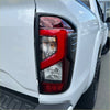 Rear view of matte black red and black taillight covers on white nissan navara 2021 st stx pro 4x4 pickup truck