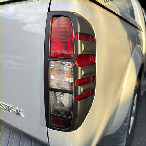 Black plastic taillight cover with red and clear lenses on silver nissan navara d40 pickup truck back side