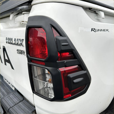 Black plastic taillight cover with red and clear lenses for white toyota hilux 2015-2020 sr back side view